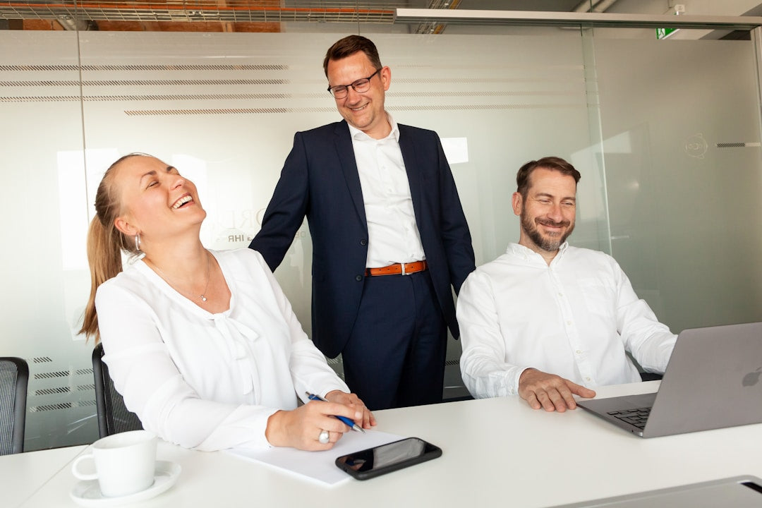 Three diverse colleagues laughing naturally together in a casual office setting